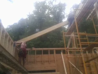 Carpenter raising a rafter beam on a new second story frame in Lanham