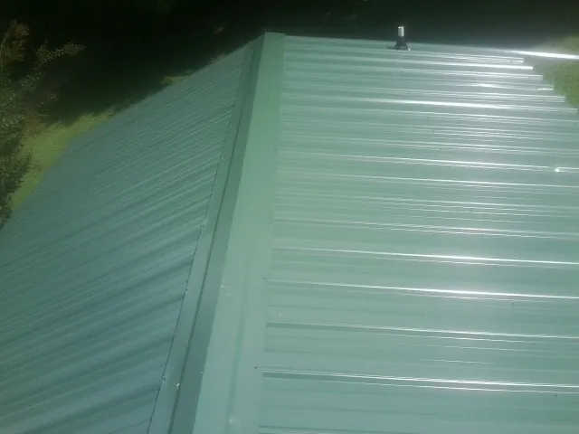 New green metal panels meeting at the ridge of a roof — Flat Roof Repair work by our crew in Lanham