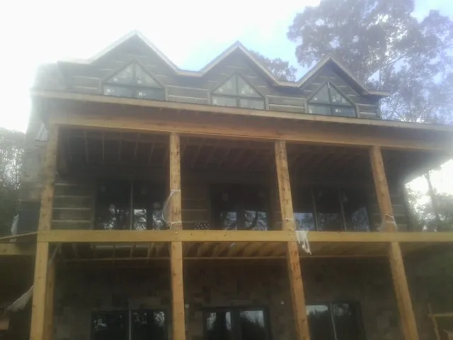 Dormers and porch framing on a large log home under construction — Roof Coating work by our crew in Lanham