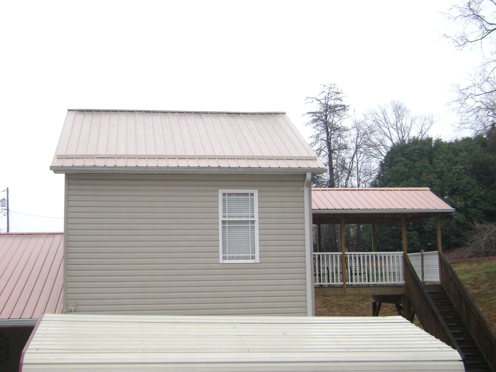 Tan metal roofs on a two story addition and attached porch, from a Roof Replacement job in Lanham